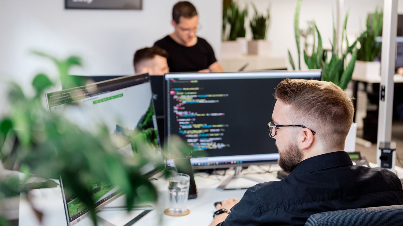 Ein Mitarbeiter in einem Büro sitzt vor zwei Monitoren